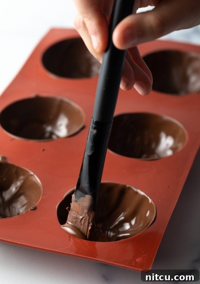 Spatula filling mold with melted chocolate.