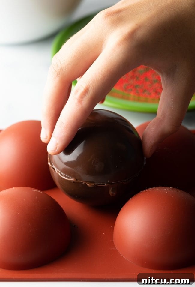 Hand topping half of chocolate mold with other half.