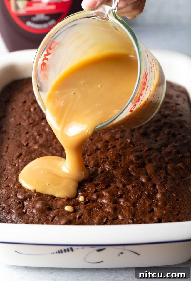 A close-up of a freshly baked cake, dotted with numerous small holes, ready to absorb the luscious caramel and condensed milk mixture for an ultimate moist texture.