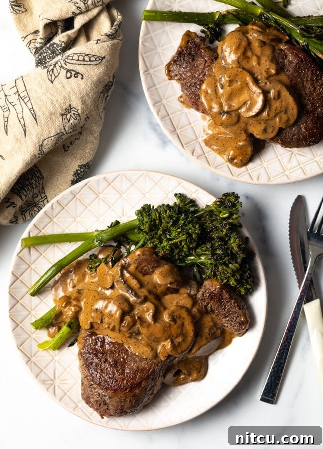 Top view of a succulent beef filet generously covered with mushroom cognac sauce and complemented by fresh broccolini.