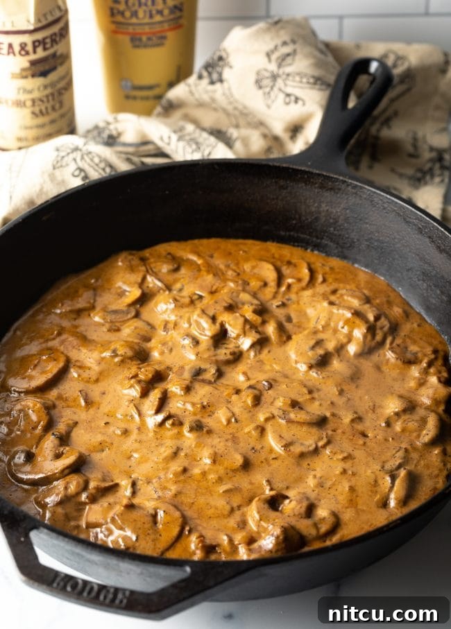 Rich mushroom and cognac cream gravy simmering beautifully in a cast iron skillet, thickening to perfection.