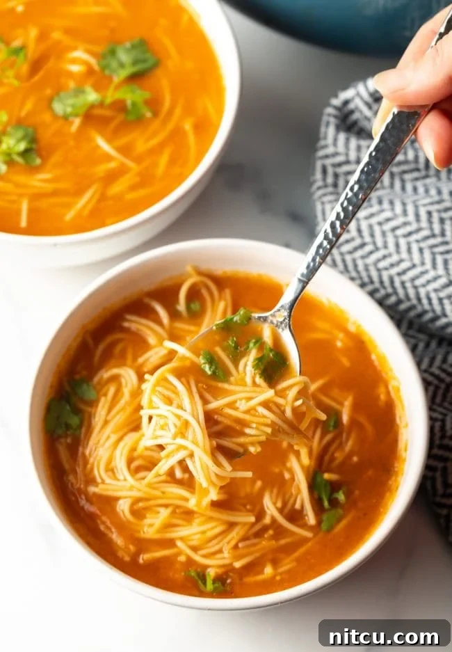 top view of a spoon scooping a bite of flavorful Mexican soup with fideo noodles