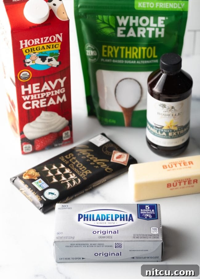 A flat lay photograph showcasing all the simple ingredients required for no-bake keto cheesecake fat bombs: cream cheese, butter, heavy cream, dark chocolate, erythritol, and vanilla extract.