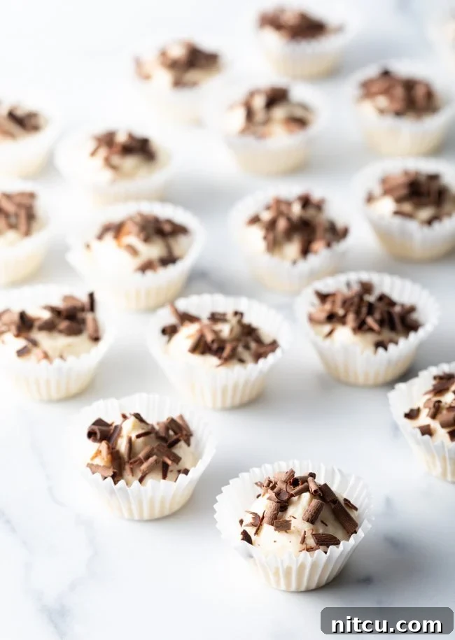 A beautiful pulled-out view of a dozen mini cream cheese and chocolate bites, perfectly arranged in their paper liners on a polished marble background, ready to be enjoyed as a low-carb treat.