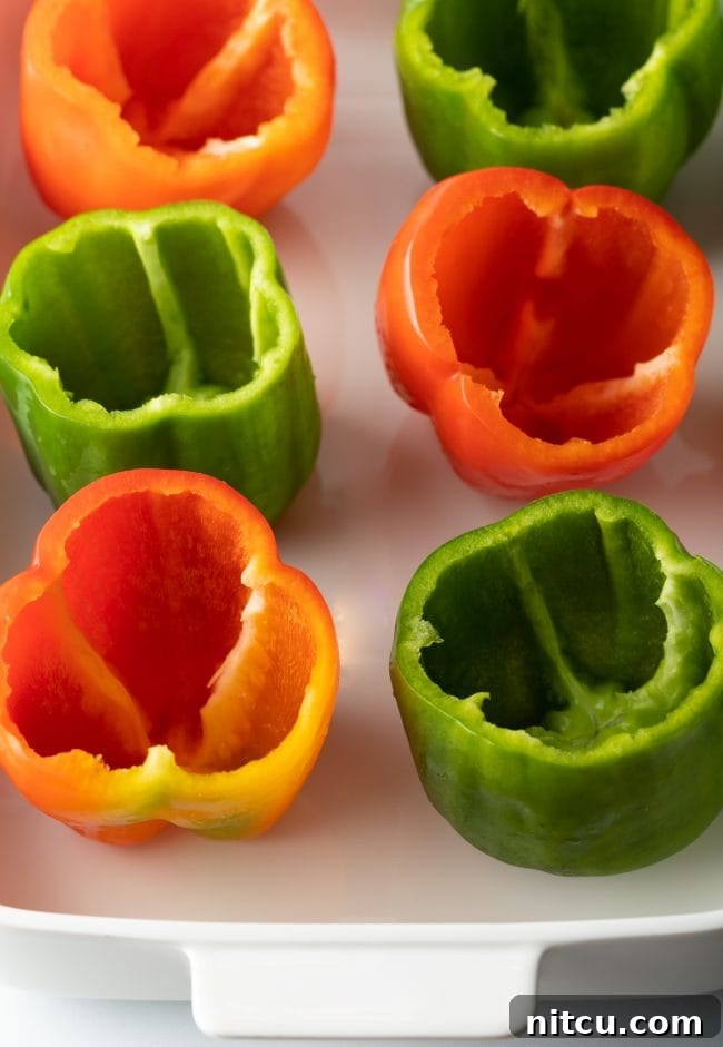 Empty seeded red and green bell peppers in a baking dish.