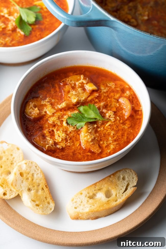 two bowls of sopa de ajo spanish soup on plates with toasted baugette slices