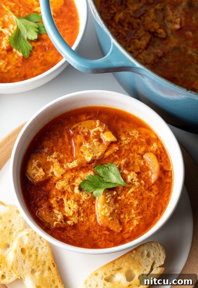 top view spanish garlic egg drop soup in a bowl on a plate with toasted baguette slices