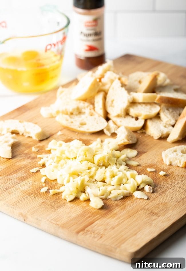 Sopa De Ajo - chopped garlic and baguette slices on a wood cutting board