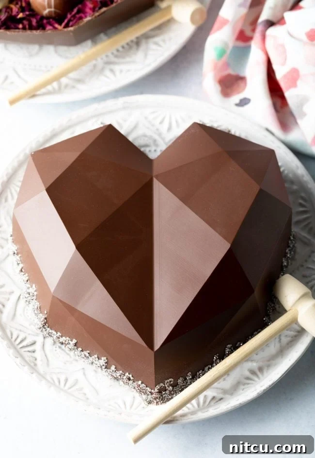A beautifully crafted breakable chocolate heart, placed on a pristine white plate, accompanied by a small wooden hammer, ready for a delightful smash reveal.