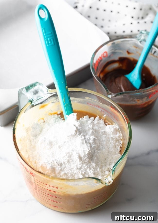 Adding powdered sugar gradually to the melted peanut butter mixture in a bowl.