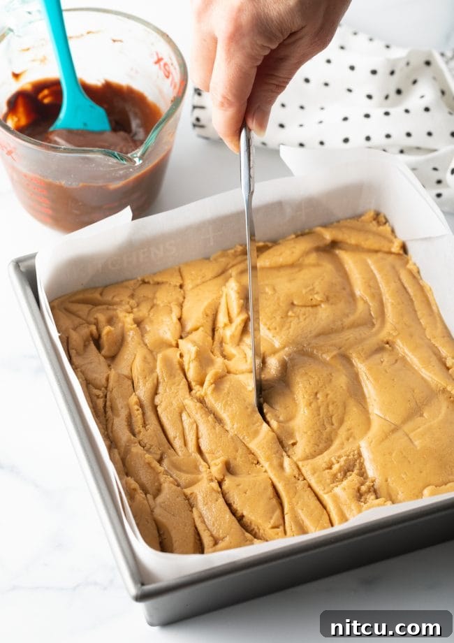 Spreading the peanut butter mixture in the baking pan and creating swirls with a knife for the chocolate layer.
