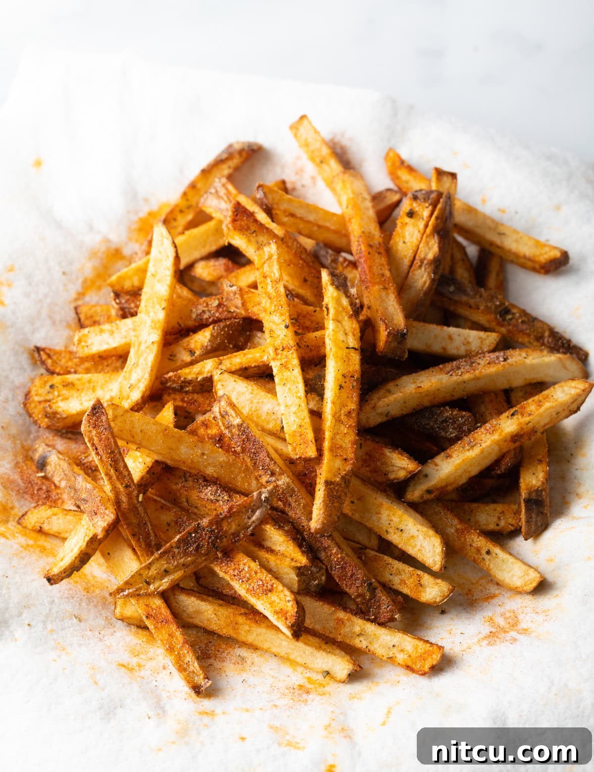 Top view sliced cajun seasoned fries on a white towel.