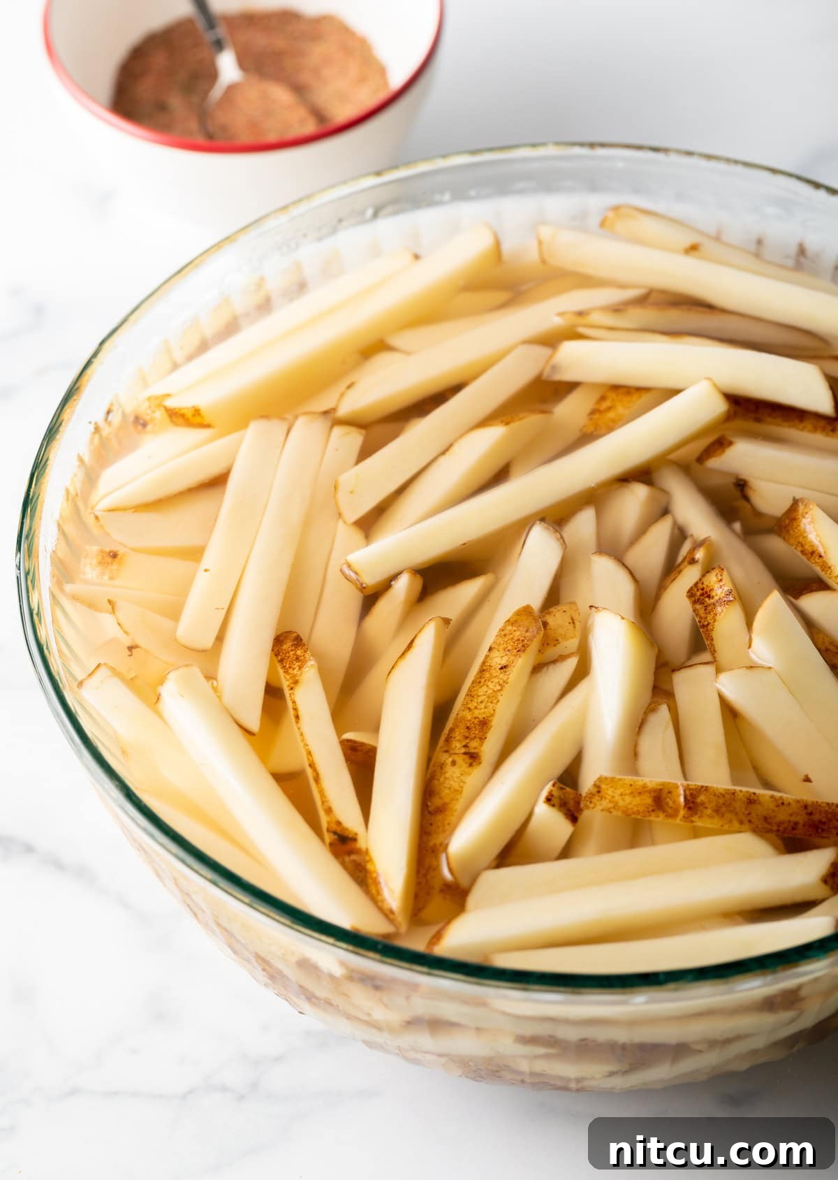 Potato slices in soaking in a bowl of water.