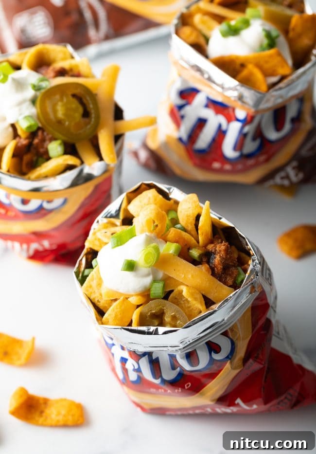 Three individual bags of Fritos, each meticulously filled with Frito chili pie, ready to be served.