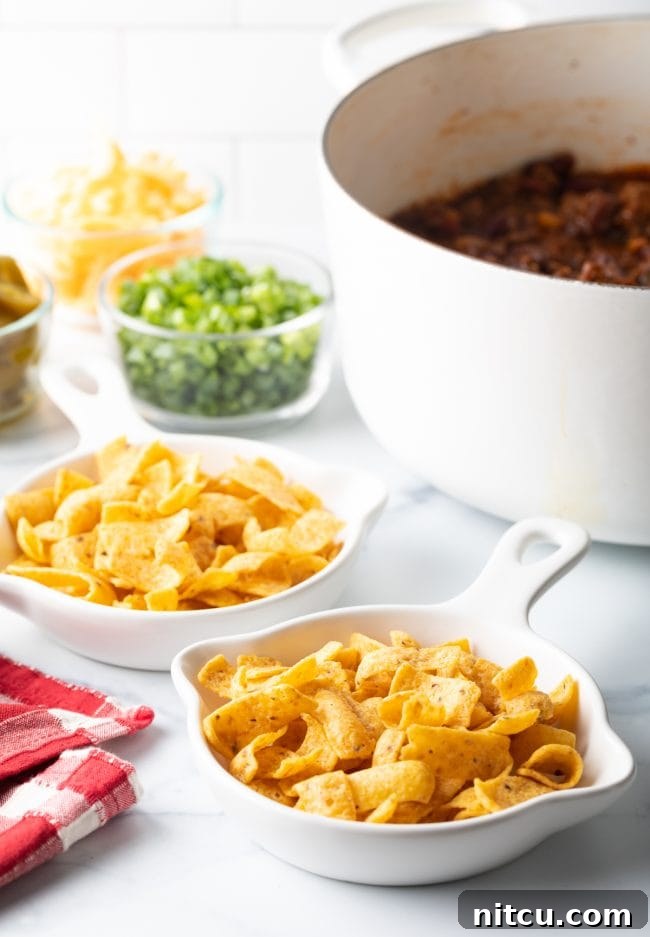 A vibrant spread of Fritos corn chips in shallow dishes, with a variety of fresh toppings arranged neatly in the background.