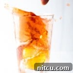 A shot glass of Red Bull about to be dropped into a glass containing whiskey, peach schnapps, and cranberry juice for a Vegas Bomb cocktail.