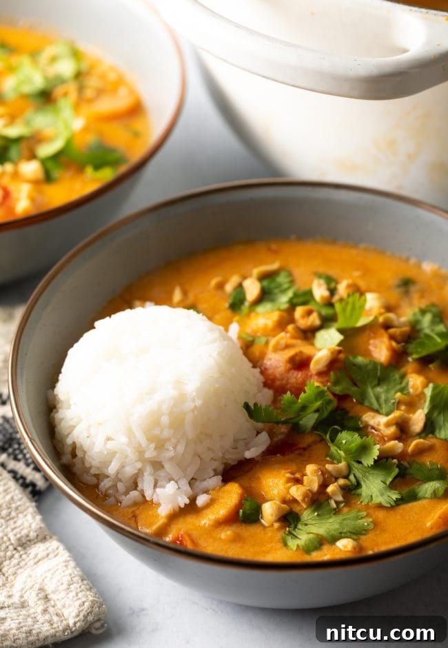 Close up of plated Maafe in a bowl with a serving of rice, showing the creamy texture and vibrant ingredients.