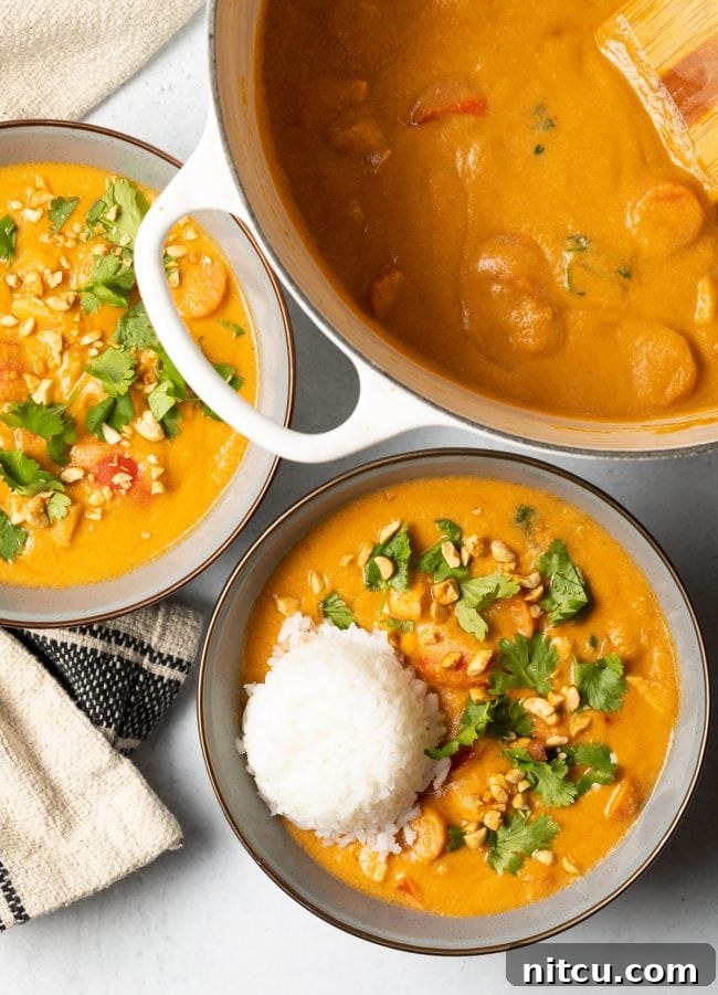 Top view of two bowls of African peanut soup with a scoop of rice nestled in each, ready to be enjoyed.
