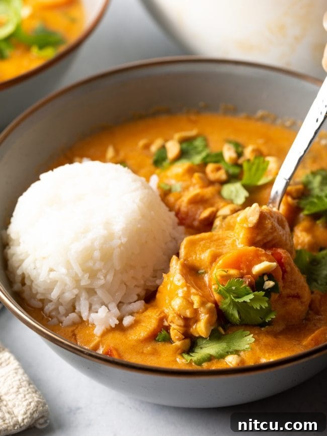 A bowl of Maafe with a scoop of rice, with a metal spoon scooping up the rich soup.