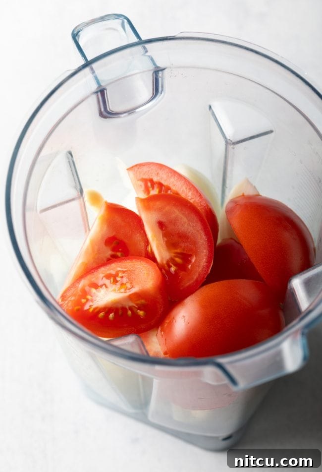 Tomatoes, onions, ginger, and garlic, key ingredients for the creamy base, placed in a blender.