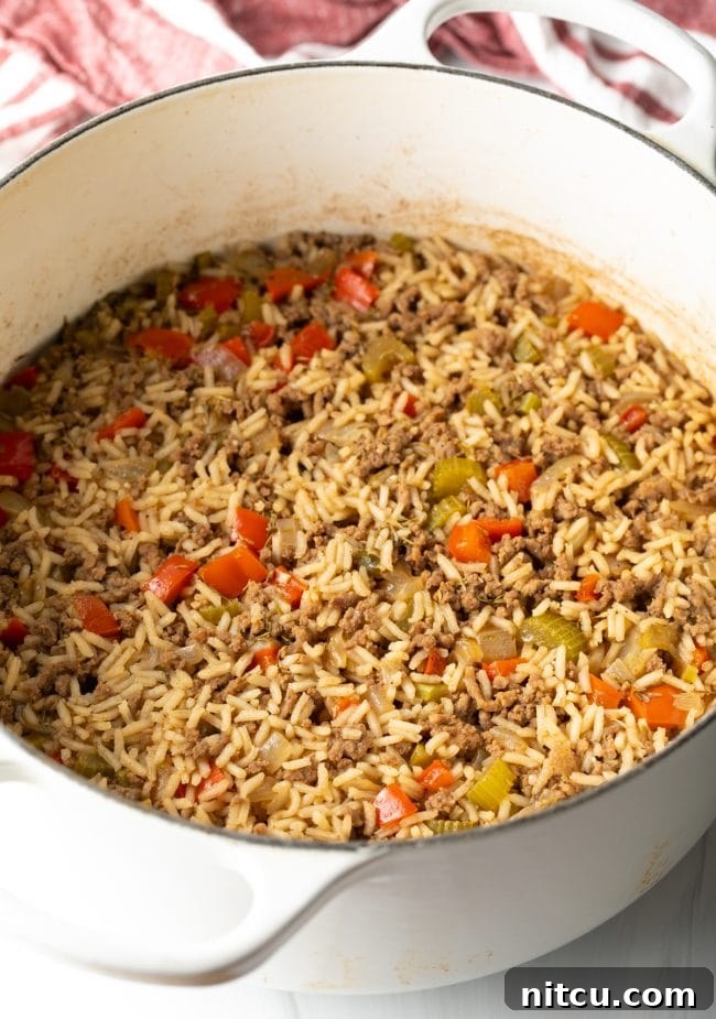 Cooked ground beef and vegetables mixed with rice in a pot.