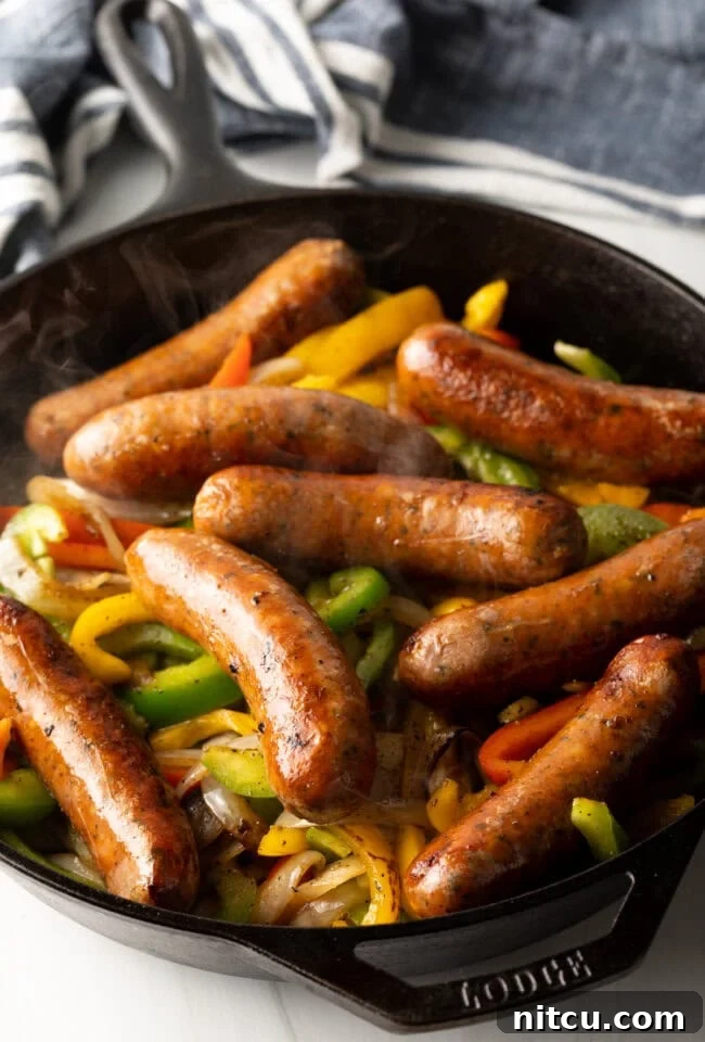 Cast iron skillet with cooked bell peppers, onions, and sausage.