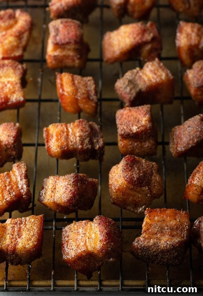 Perfectly cubed and smoked pork belly burnt ends resting on a wire rack, ready for the next step.
