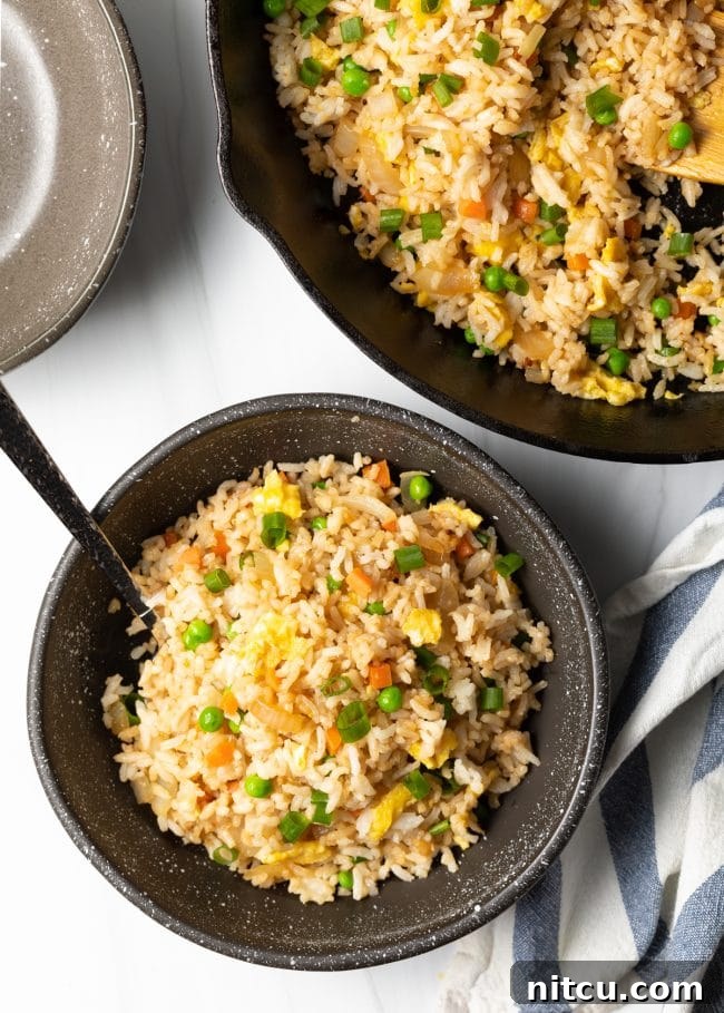Top down view bowl of Japanese fried rice next to skillet of food, highlighting a full meal spread.