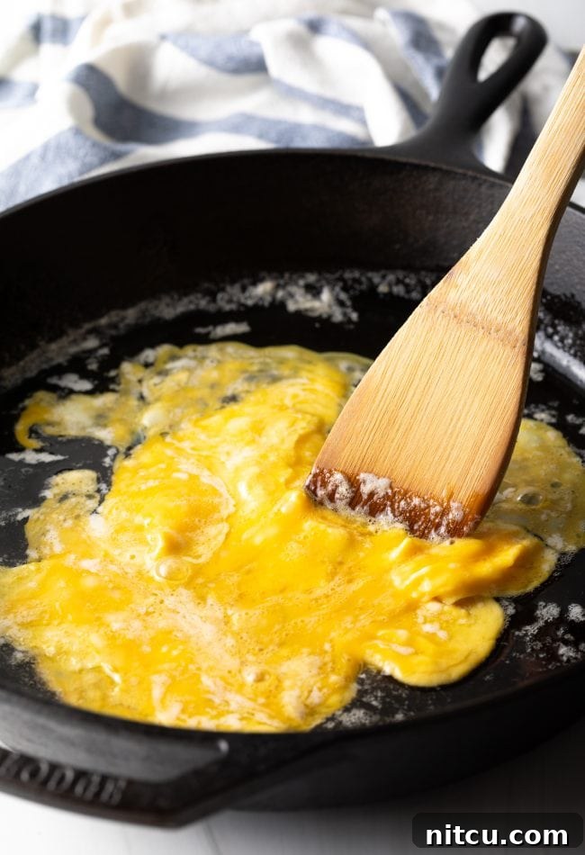 Eggs being scrambled gently in a pan, fluffy and golden.