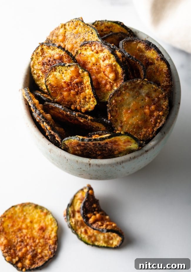 Top down view of a rustic speckled bowl filled to the brim with air-fried zucchini chips, ready to be enjoyed.