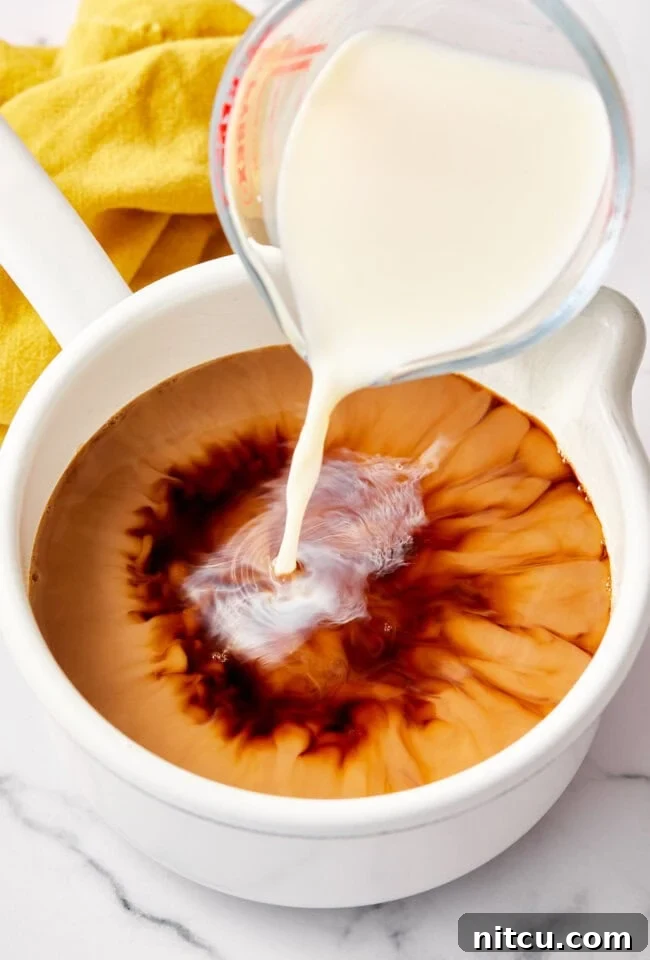 Milk blending into the rich chai tea concentrate, creating a beautiful creamy texture and color for the homemade latte.