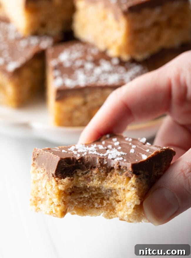 Hand holding Peanut Butter Rice Krispie Bar with bite taken to camera.
