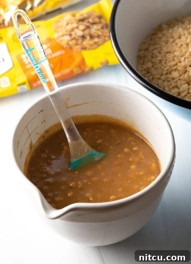 Large white measuring cup with melted butterscotch chips and peanut butter, combined with a spatula.