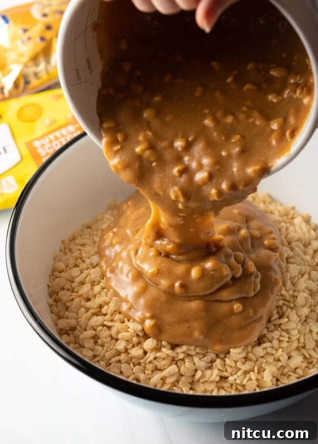 Hand pouring butterscotch and peanut butter combination onto a bowl of Rice Krispies cereal.
