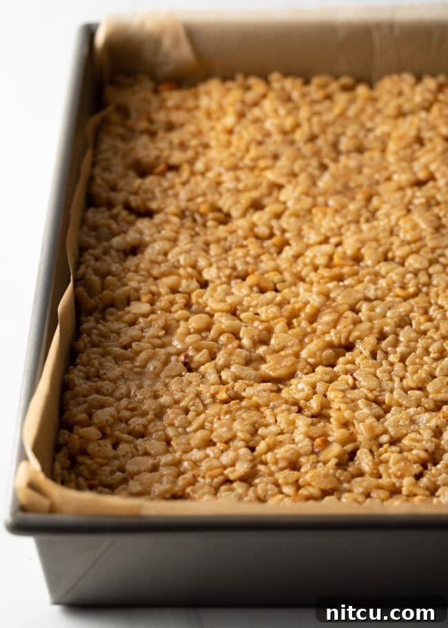 Crispy rice cereal, peanut butter, and butterscotch combo pressed into a pan.