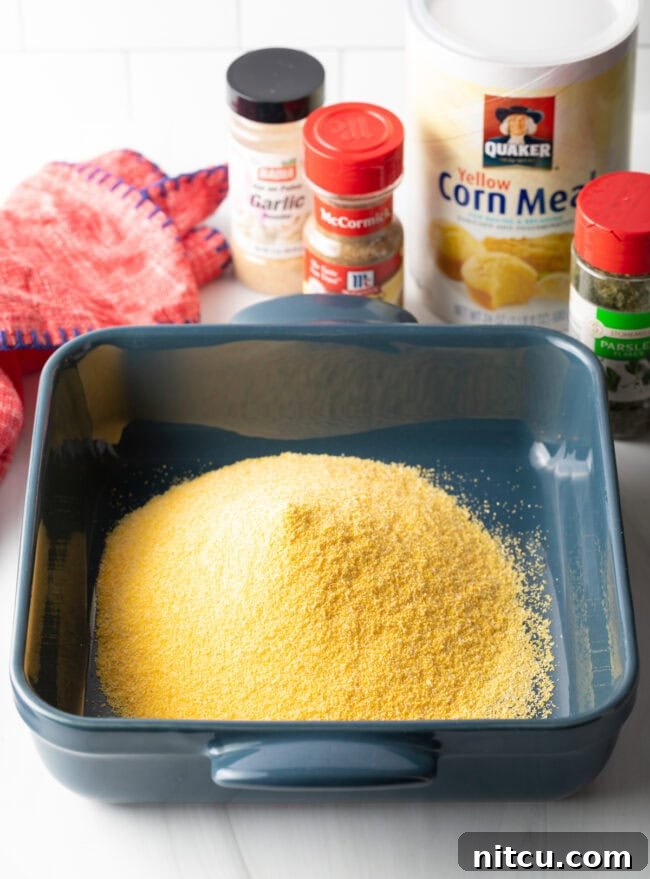 Square baking pan filled with golden yellow cornmeal, ready for seasoning.
