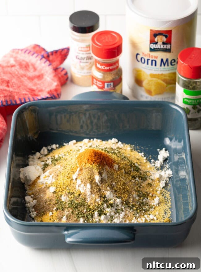 A mix of dry spices, including dried parsley and red pepper flakes, ready to be combined with cornmeal.
