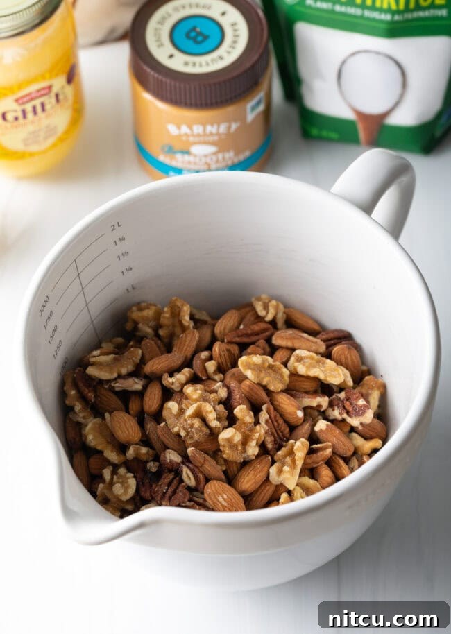 White mixing bowl with raw almonds, pecans, and walnuts, ready to be processed.