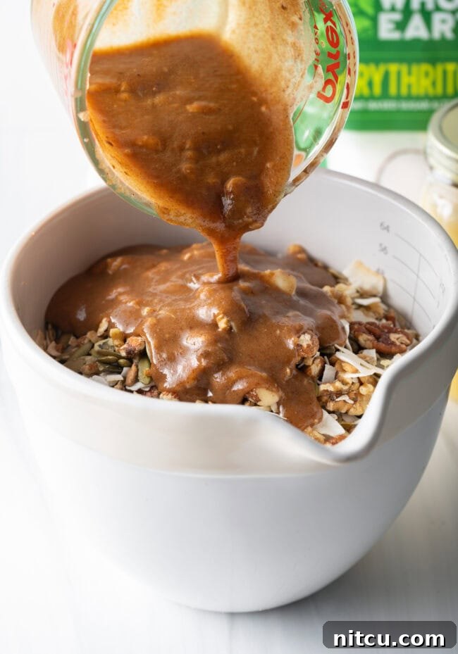 Keto granola mixture spread evenly on a baking sheet before baking.