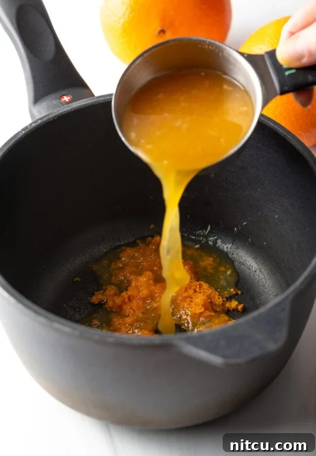 Hand pouring orange juice and zest into a pot. A hand carefully pouring freshly squeezed orange juice and fragrant zest into a saucepan. This visual highlights the initial step of combining the liquid citrus components with the zest, setting the stage for the curd's flavor development.