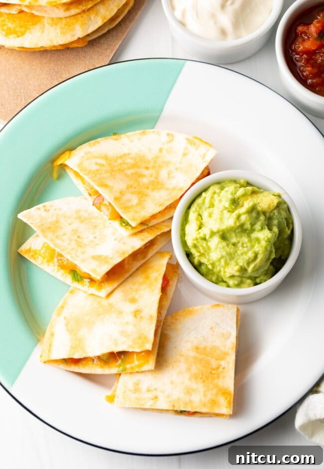 Top down view four triangles of quesadilla on a plate with ramekin of guacamole.
