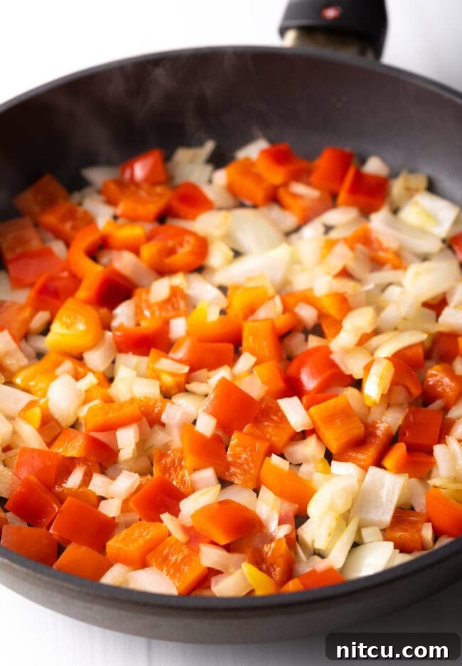 Chopped onions and red pepper in a skillet.