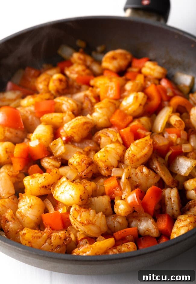 Chopped onions, bell peppers and shrimp in the skillet. 