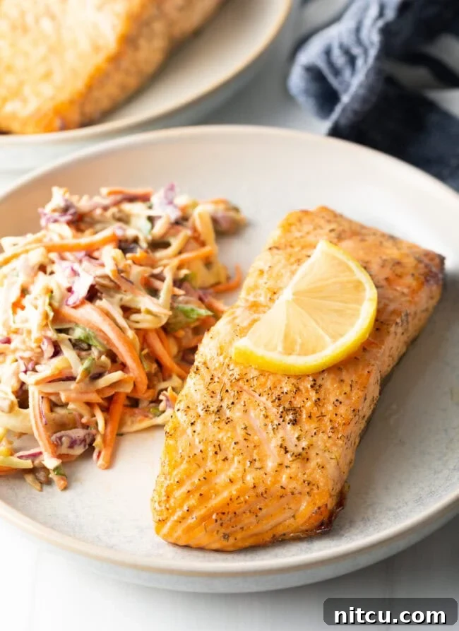 Plate of salmon with coleslaw. Delicious Air Fryer Frozen Salmon Fillet with Skin recipe.
