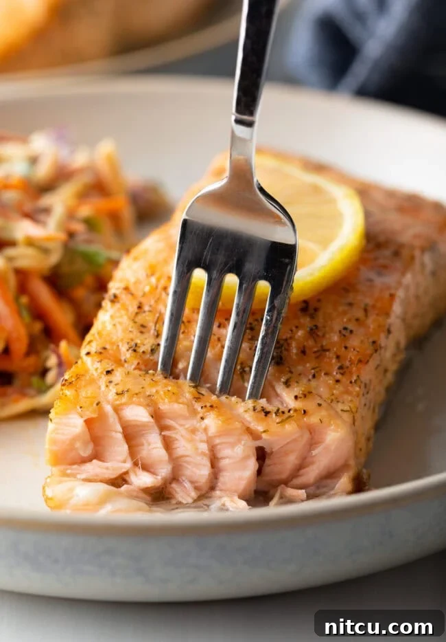 Fork taking a bite of salmon. Crispy skin, flaky meat.