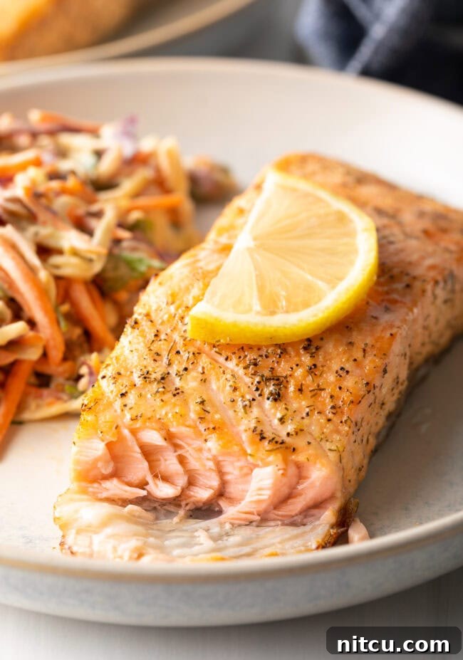 Piece of fish with bite taken out, on a plate. Air fryer salmon with crispy skin.