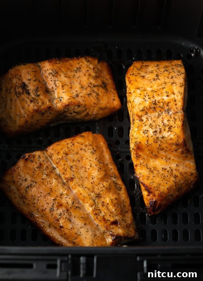 Cooked salmon fillet in the air fryer basket, perfectly golden.