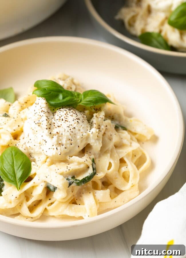 Final view of a bowl of lemon ricotta pasta garnished with fresh basil.