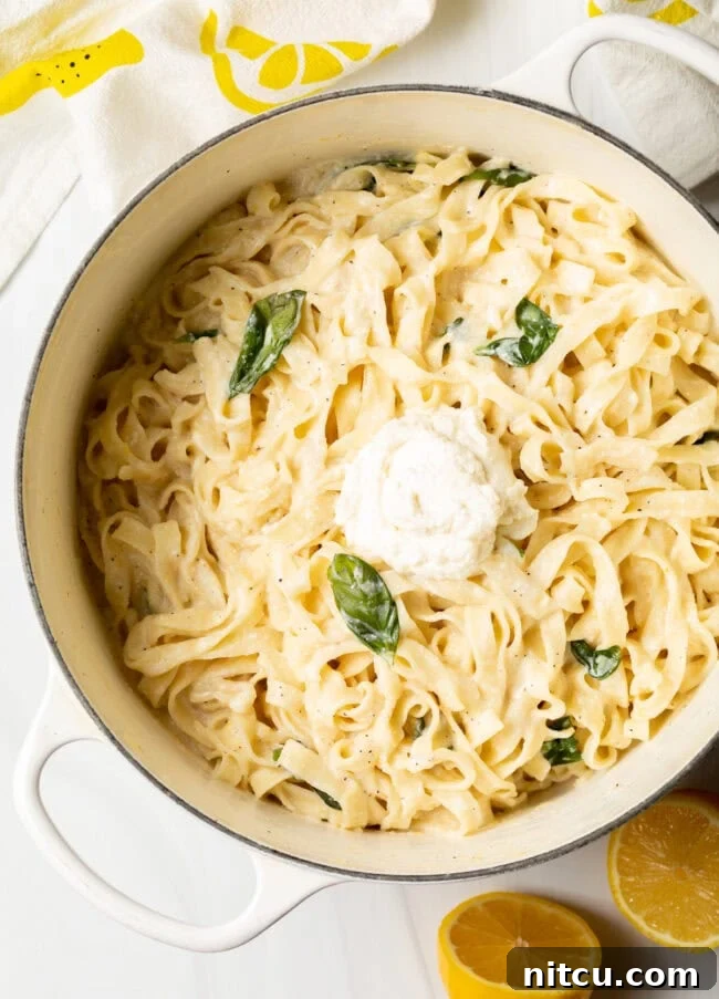 Top down view of a large pot of fettuccine noodles with creamy ricotta and lemon sauce, ready to be served.