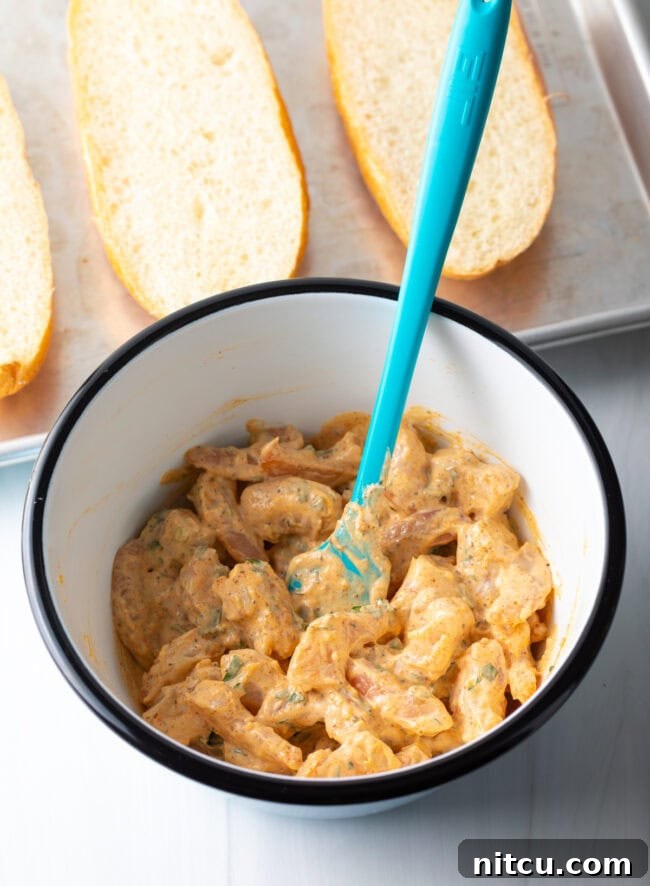 All shrimp bread filling ingredients perfectly combined in a bowl with a blue spatula, showing the creamy, textured mixture.